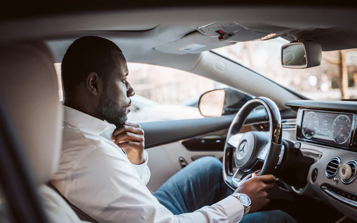 A man in a white shirt driving to work