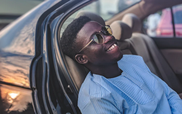 A smiling passenger looking out from the back seat of a car
