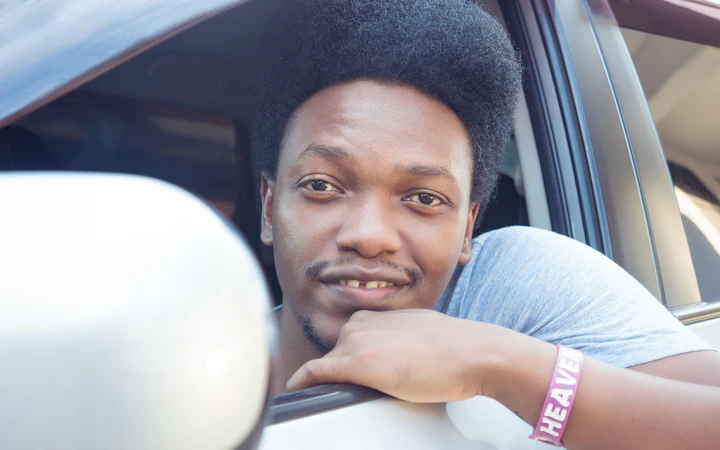 A smiling man leaning out of a car window