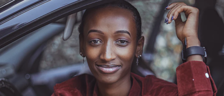 A calm, smiling woman in the seat of a car